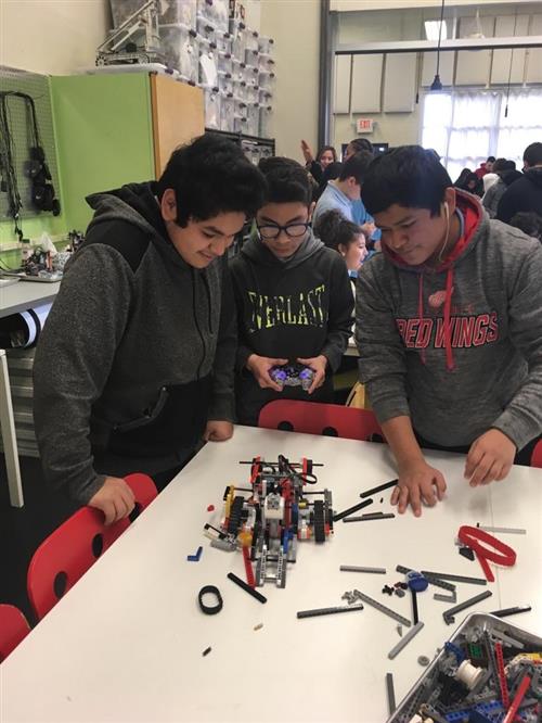 3 students putting together a robot 